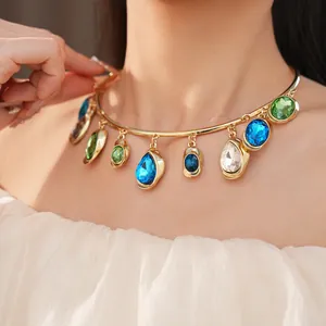 Close-up of a gold choker necklace with teardrop blue and green crystals on a model.