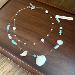 Detail shot of blue ocean style necklace with seashells, pearls, and glass beads.