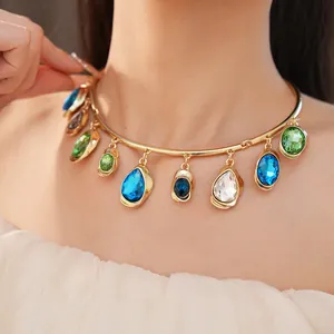 Detailed view of a gold collar necklace with vibrant teardrop and oval crystal pendants