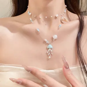 Close-up detail of a blue ocean-themed necklace with a jellyfish pendant and pearls on model.