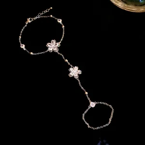Macro detail of 14k gold plated hand chain bracelet with sparkling zircon flowers.