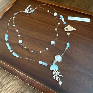 Detailed view of ocean-themed necklace featuring light blue jellyfish pendant and pearls