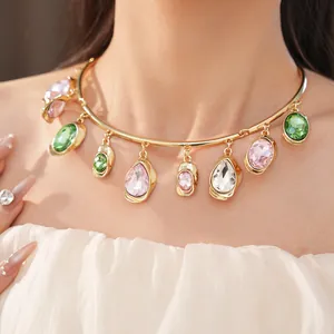 Close-up detail of a gold oversized choker necklace with colorful teardrop crystals on model