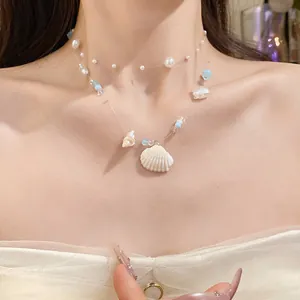Close-up detail of summer ocean-inspired necklace with shells and pearls on a model.