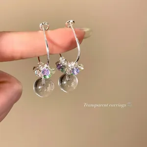 Close-up detail of colorful crystal hoop earrings featuring clear transparent glass balls