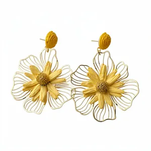 Elegant yellow raffia and gold metal flower earrings on a clean white background.