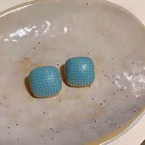 Detail view of square turquoise stud earrings with elegant gold honeycomb lattice pattern