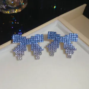 Detailed macro view of exquisite gradient blue rhinestone bow earrings in a luxury jewelry box