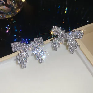Close-up of sparkling pixel-style bow-knot stud earrings with full rhinestone pavé.
