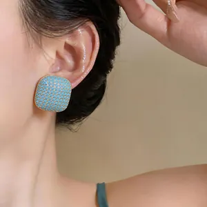 Detailed view of luxury square turquoise textured stud earring worn on a model ear