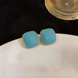 Close-up detail of vintage square stud earrings with turquoise blue beads and gold frame