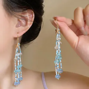 Vue détaillée de boucles d'oreilles pendantes à perles et étoile de mer faites main