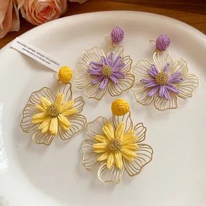 Detailed macro view of handmade raffia flower earrings with hollow metal petals