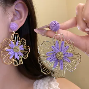 Detailed macro view of handmade purple raffia and gold wire flower petal earrings.