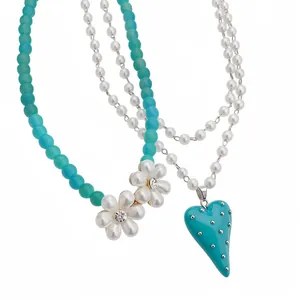 Collier multicouche avec perles turquoise, breloques fleurs et pendentif cœur.