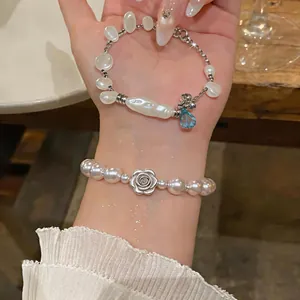 Close-up of elegant irregular pearl and silver rose bracelets on model's wrist