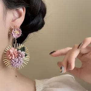 Detalle de primer plano de pendientes de girasol coloridos usados en una oreja de modelo
