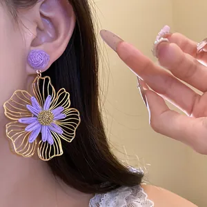 Close-up of large purple raffia flower earring with gold-toned hollow metal frame.