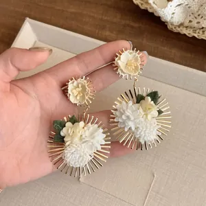 Detalle de pendientes florales de gran tamaño con pétalos de tela y acabado dorado