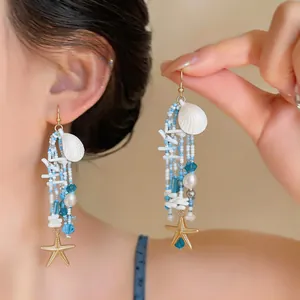 Détail de boucles d'oreilles en perles de style plage avec breloques coquillage et étoile