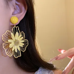 Close-up detail of yellow raffia flower earring with intricate golden wireframe petals