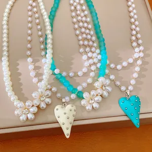 Vue détaillée de colliers de perles élégants avec fleurs de perles et pendentifs cœur.