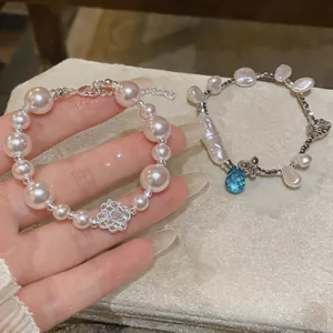 Close-up of elegant irregular pearl bracelets with silver flower and blue crystal charms