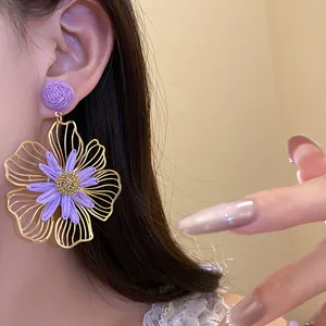 Detailed macro view of elegant purple raffia and gold hollow flower stud earrings for women