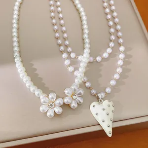 Vue détaillée de colliers de perles avec breloques fleurs et pendentif cœur clouté