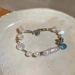 Detailed view of elegant irregular baroque pearl bracelet with a blue crystal pendant.