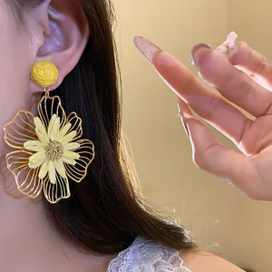 Detailed close-up showing artistic yellow metal and raffia flower earrings on a model's ear