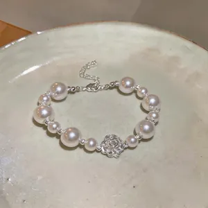 Detailed view of an elegant pearl bracelet featuring a central silver rose charm.