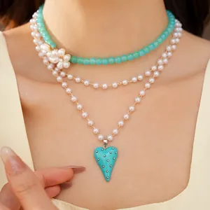 Gros plan d'un collier de perles multicouche avec un pendentif en forme de cœur