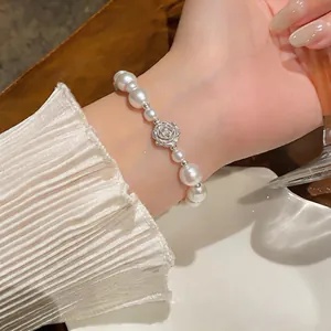 Close-up detail of elegant irregular pearl bracelet featuring a delicate silver rose charm