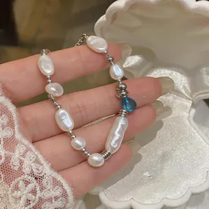 Detailed shot of an irregular pearl bracelet with a blue teardrop bead in a shell box