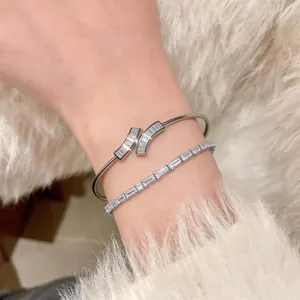 Close-up of 18k gold plated open bangle and sparkling baguette zircon line bracelet