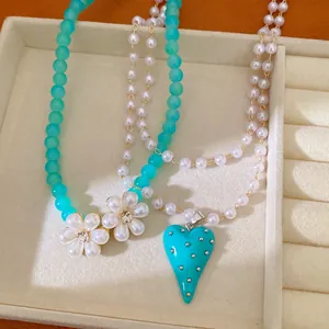Vue détaillée du pendentif cœur turquoise et des colliers de perles en fleurs dans un plateau.