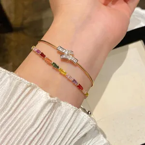 Close-up of 18k gold plated bangle and colorful zircon bracelet worn on wrist