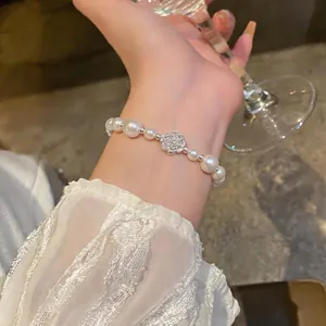 Close-up of elegant French style pearl bracelet with silver camellia charm on wrist