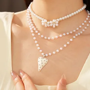 Vue détaillée des colliers de perles superposés avec un pendentif en forme de cœur et fleur
