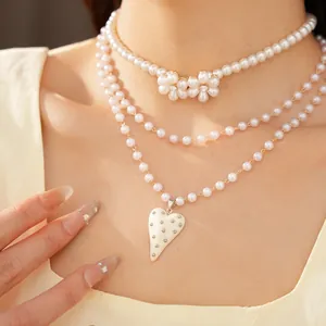 Détail d'un collier de perles multicouches avec pendentifs cœur et fleur strass