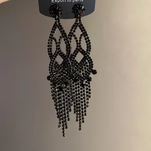 Close-up of black rhinestone fringe earrings with elegant hollow patterns and silver pins