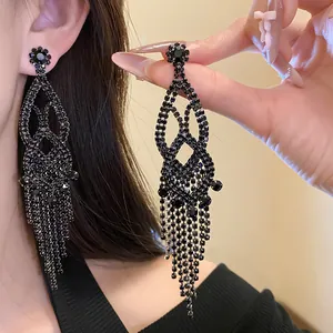 Close-up of black rhinestone tassel chandelier earrings with intricate hollow design