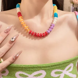 Detailed shot of vibrant rainbow acrylic beaded necklace worn on model's collarbone
