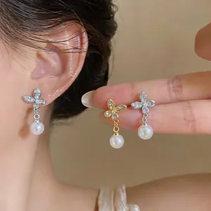 Detailed macro view of gold and silver plated butterfly earrings with pearls and zircons.