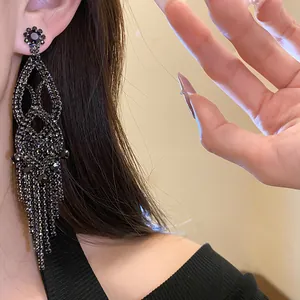 Detailed close-up showing luxury black rhinestone hollow tassel earrings worn on ear