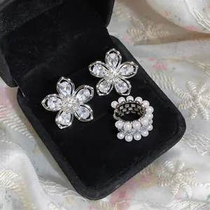 Detailed view of French style zircon flower ear clips and a pearl encrusted ear cuff.