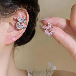 Dettaglio di eleganti ear cuff in zirconia a farfalla, senza buco, nei colori rosa e bianco