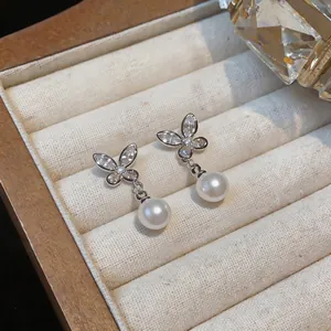 Close-up of elegant 18k gold plated butterfly earrings with white pearls and zircons.