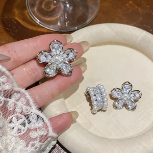 Close-up of elegant French style zircon flower clip earrings and a white pearl ear cuff
